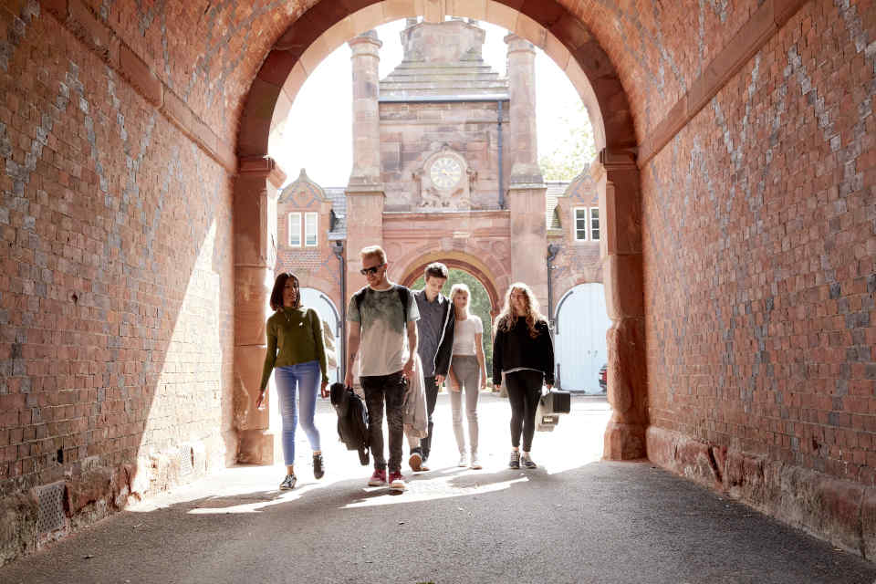 Students walking on campus with music equipment