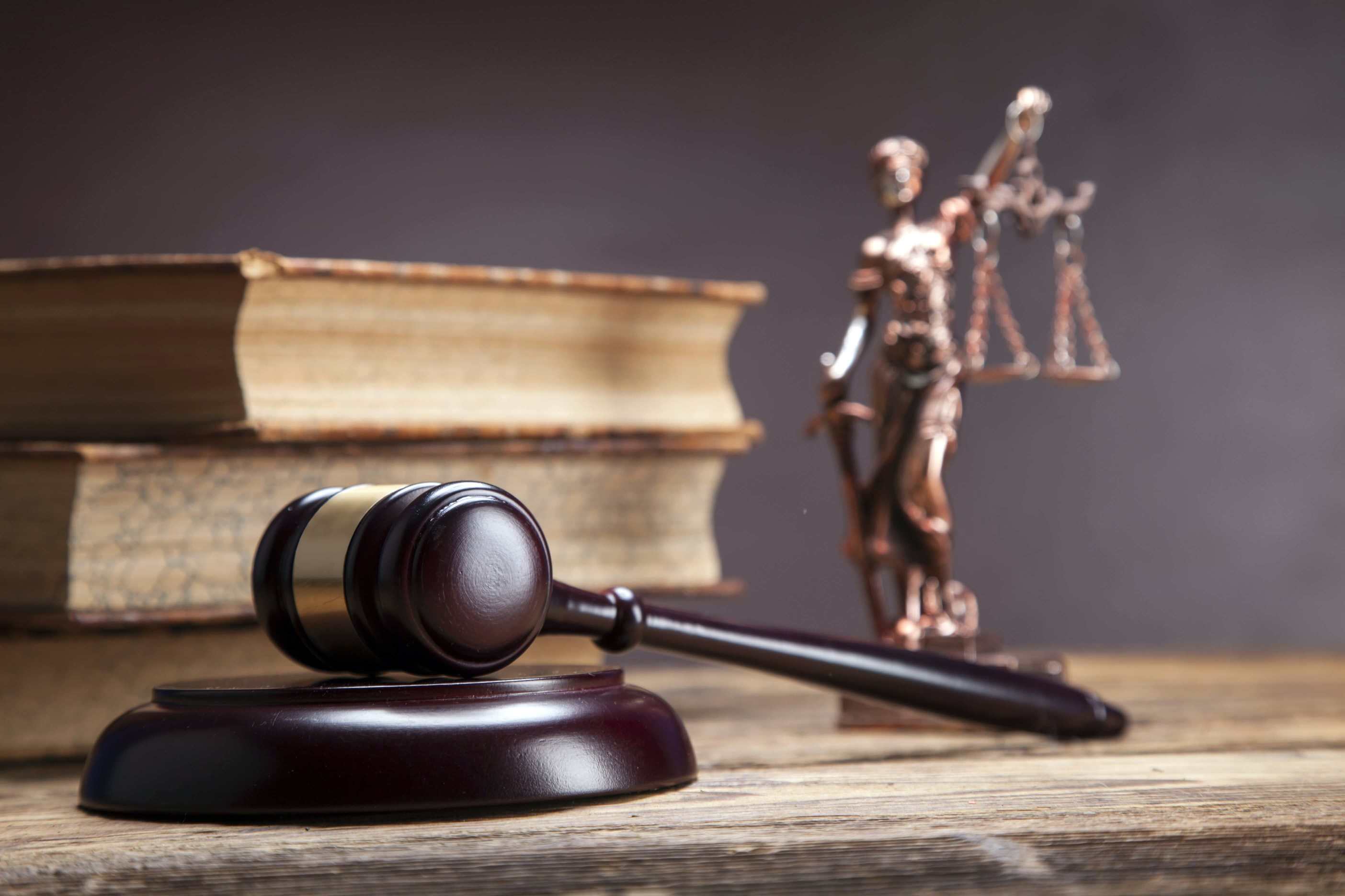 Books in the background with the statue of justice and gavel 