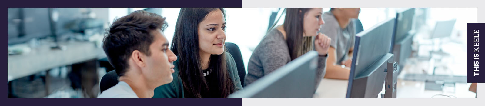 Two students working at a computer in a classroom. 